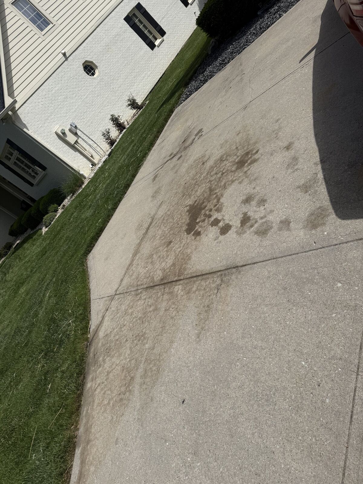 Concrete driveway before pressure washing, with dark stains